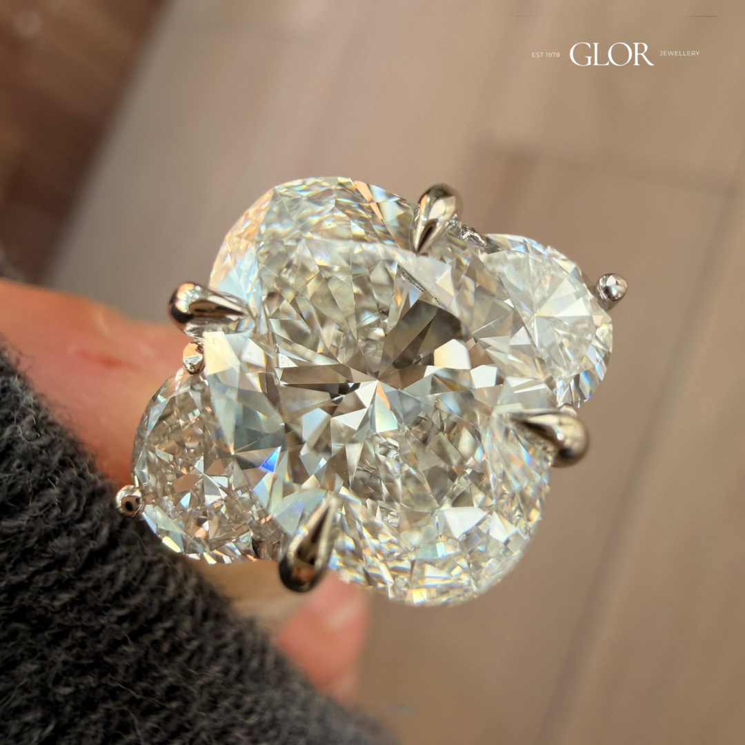 Close-up of a three-stone engagement ring with a cushion-cut center diamond, pear-shaped side diamonds, and a white gold setting.